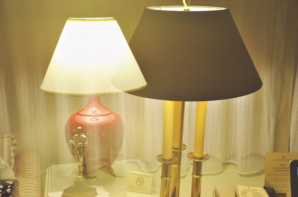 Two table lamps with pale and dark drum shades glowing side by side