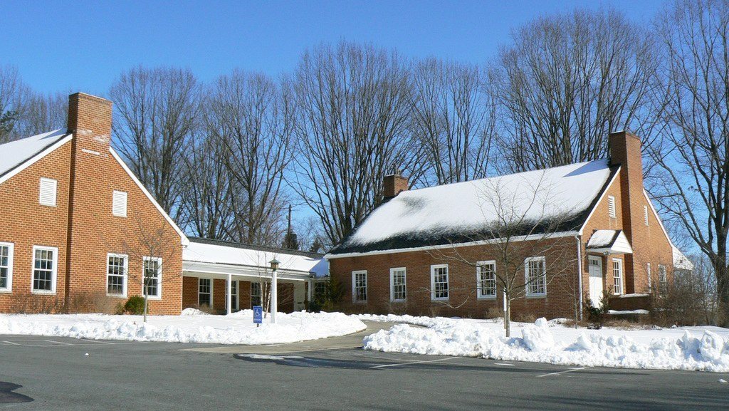 Red brick colonial homes with white trim beside a quiet road in winter