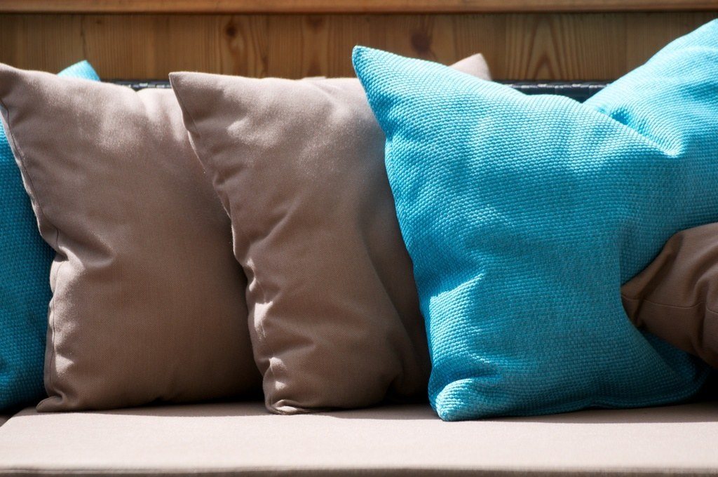 Teal and taupe cushions arranged along a bright sofa